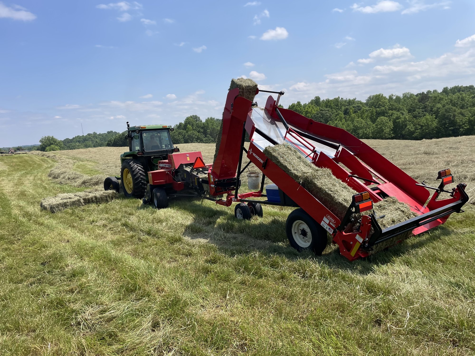 Norden accumulator loading fresh square bales behind a John Deere