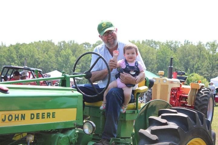 Granddad and toddler on the vintage John Deere