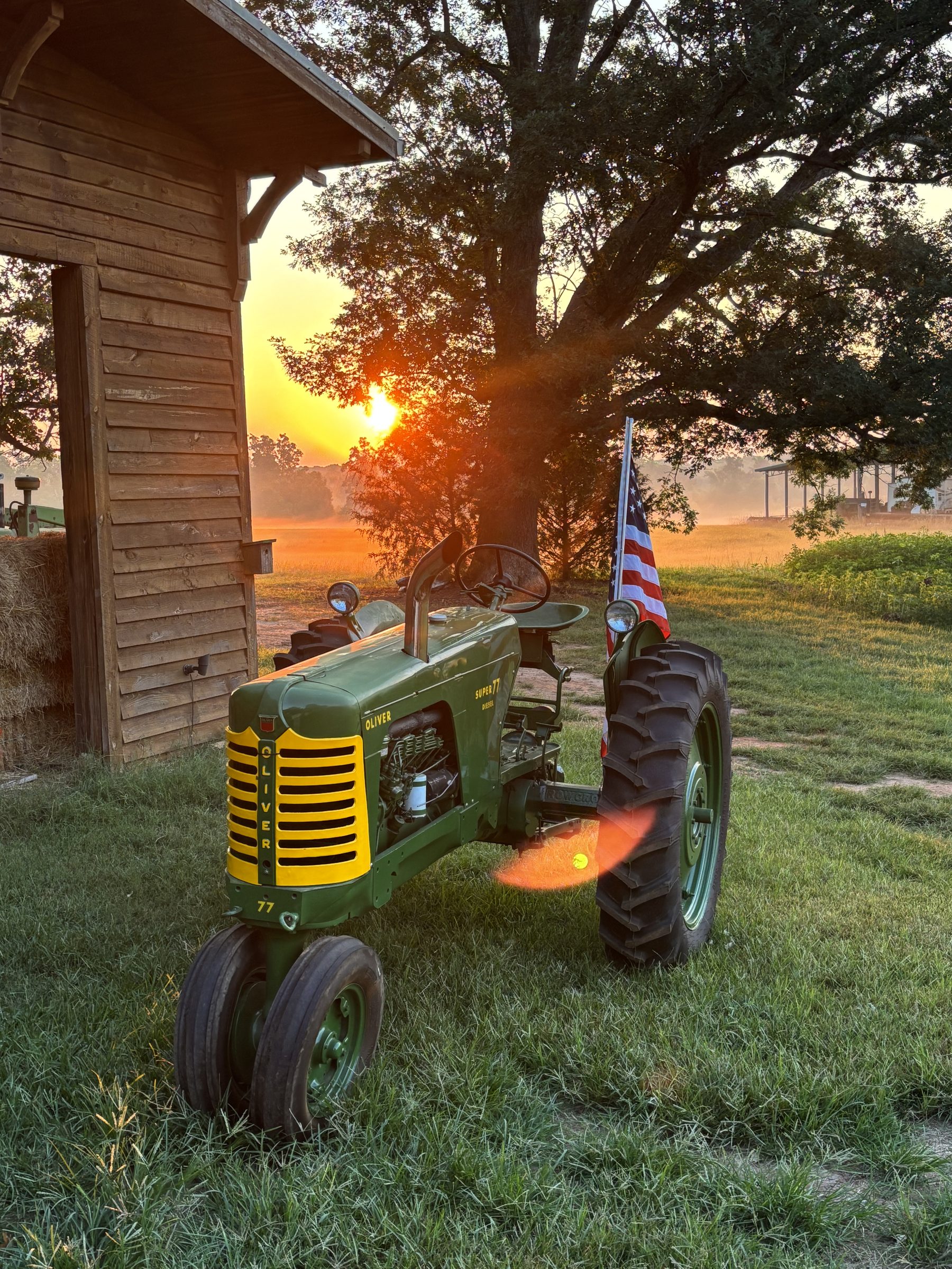 Vintage Oliver Super 77 tractor with American flag at sunrise