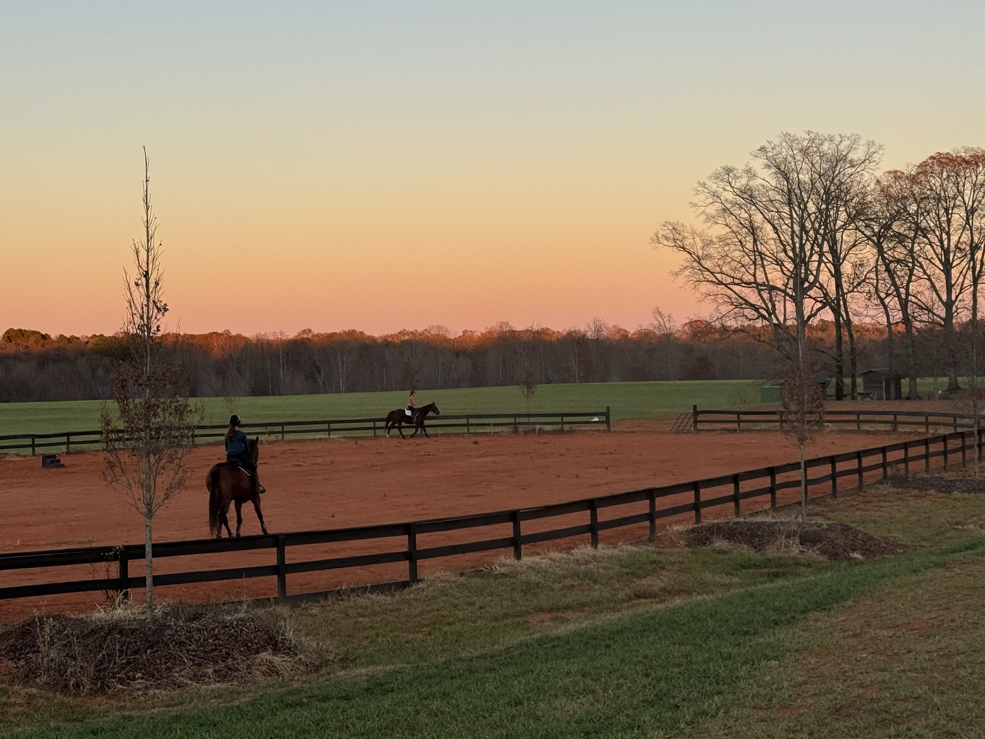 Two riders working in the arena at sunset